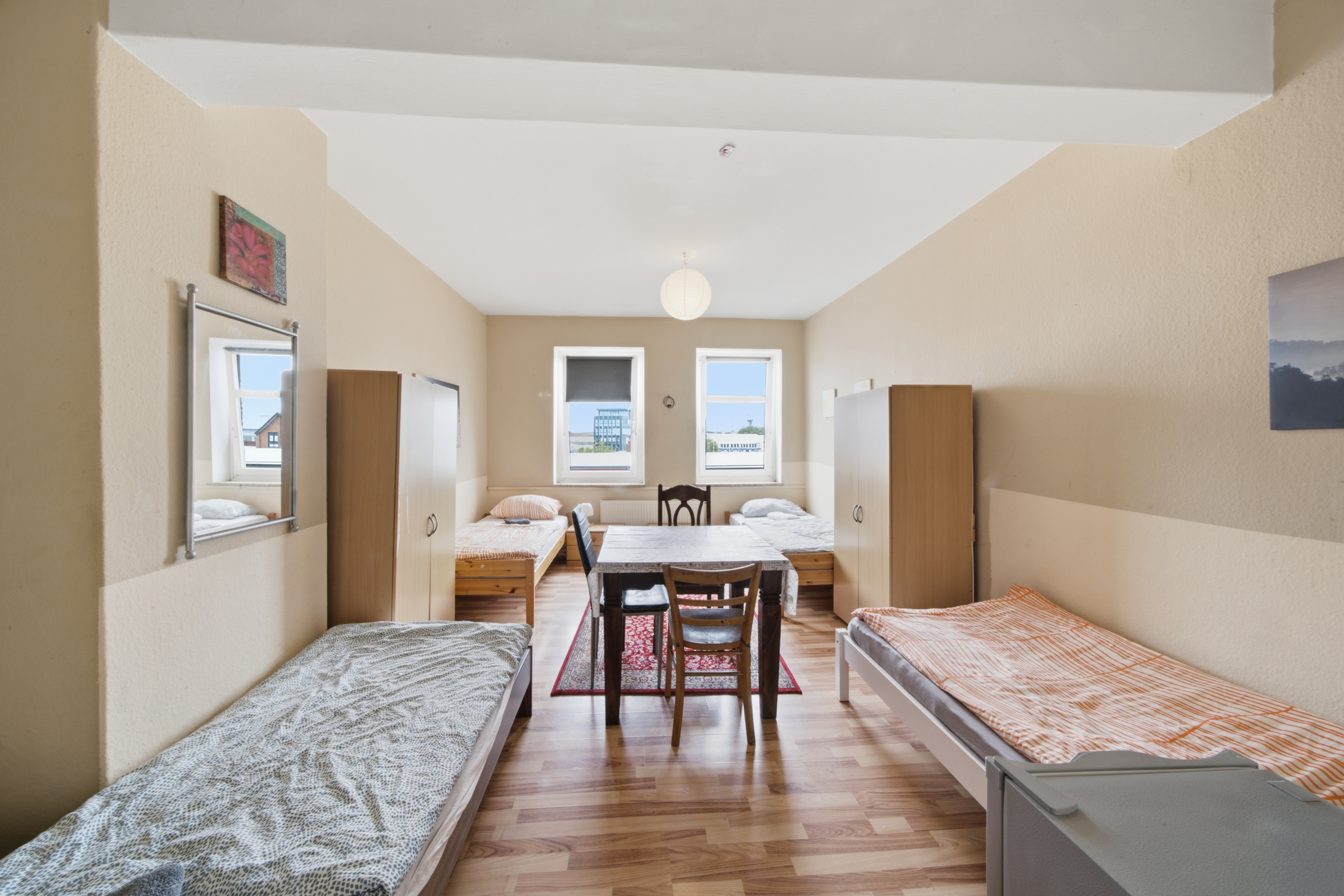 Mehrbettzimmer mit Tisch und Schränken